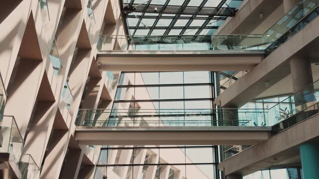 Still view of a modern atrium with glass railings and overhead skylight.