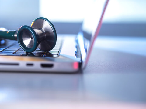 A medical stethoscope rests on a laptop keyboard for telemedicine