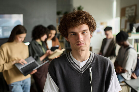 Confident young male student with wired earphone in class