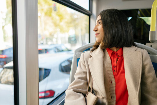 Woman sitting on a bus and looking out the window while traveling
