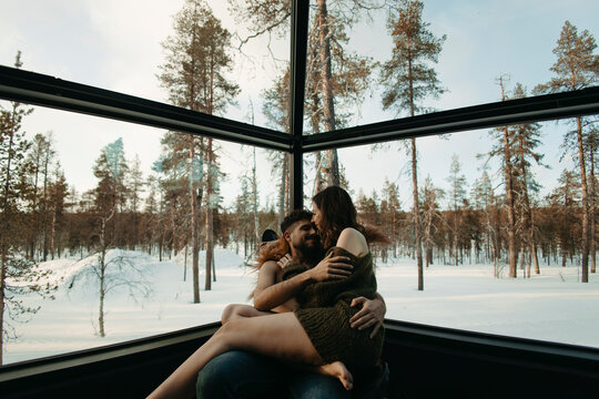 A romantic couple enjoys a winter getaway inside a glass cabin