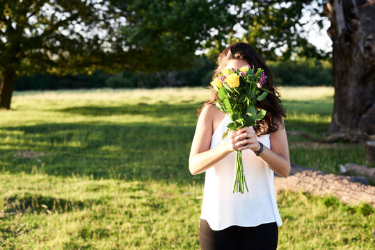Young woman hiding behind bunch of flower