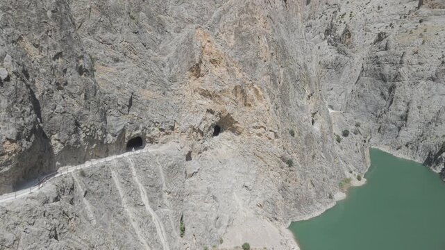 4K 10-bit drone shot flying forward low over the hand-carved stone road heading into dark rock tunnels in Kemaliye, Turkey