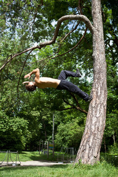 Germany, Bavaria, Young man doing parcour training in park