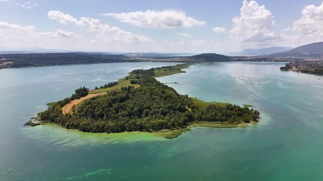 St. Peter's Island in Lake Biel, Biel Bienne District, Bern, Switzerland, revealing the forested peninsula, turquoise shallows and protected wetlands, drone orbit.