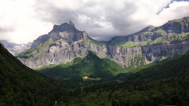 Cirque du Fer-a-Cheval, Sixt-Fer-a-Cheval, Haute-Savoie, France, revealing towering limestone cliffs, alpine forest, glacial cirque and rugged mountain walls, drone forward flyover.