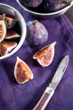 Sliced and whole figs and a pocket knife on cloth