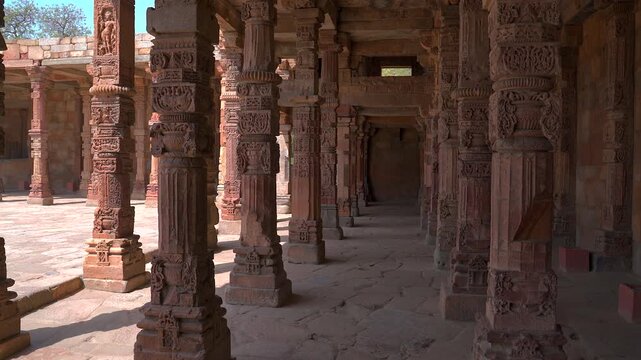 Static wide shot of the historic intricately carved sandstone pillars inside the Quwwat-ul-Islam mosque cloister at Qutb complex in New Delhi, India.