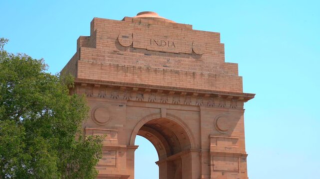 Static low angle shot of the top section of India Gate showing the engraved word India and carved inscriptions in New Delhi, India.