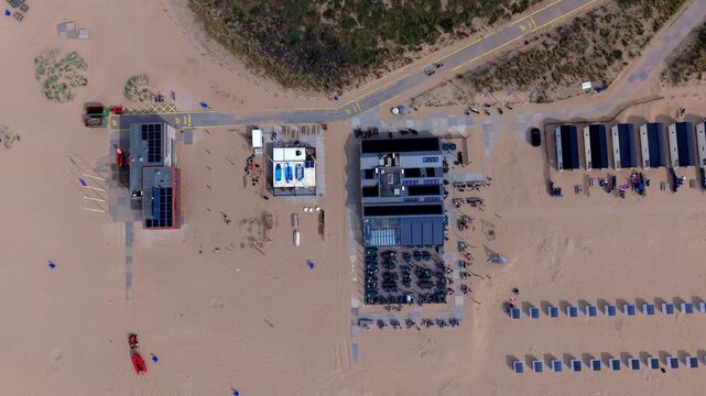 Aerial view video clip of Katwijk aan Zee beach resort top down, rescue station, restaurant pavilion terrace, beach houses, windbreaks, and coastal dune path in South Holland, Netherlands