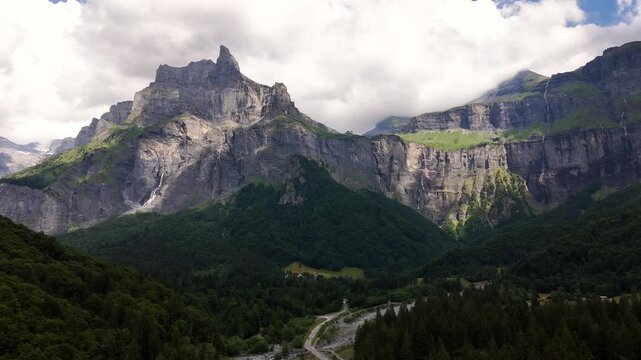 Cirque du Fer-a-Cheval, Sixt-Fer-a-Cheval, Haute-Savoie, Auvergne-Rhone-Alpes, France, revealing towering limestone cliffs, alpine forest and glacial cirque, drone pullback.