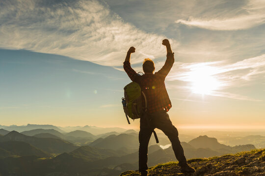 Austria, Salzkammergut, Hiker reaching summit, raising arms, cheering