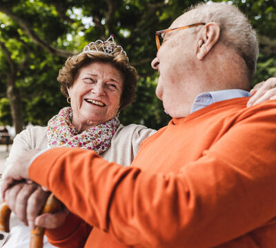 Happy senior couple sitting in park, woman wearing crown