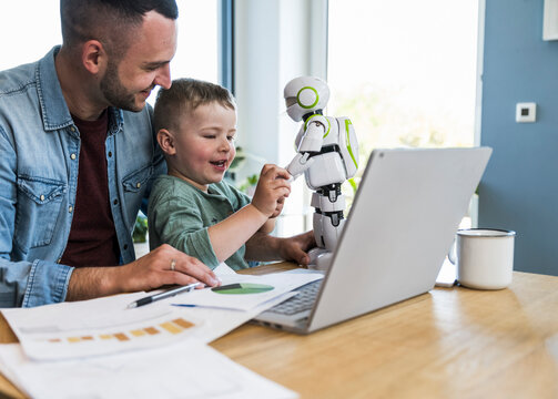 A father and son play with a toy robot at home