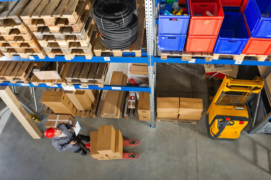 A warehouse worker in Munich, Germany checks inventory using a clipboard in a Bavarian setting