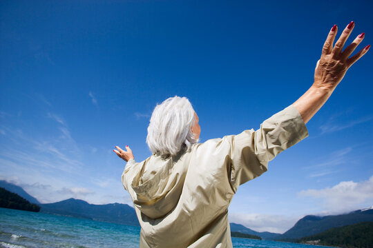 Germany, Bavaria, Walchensee, Senior woman cheering, rear view
