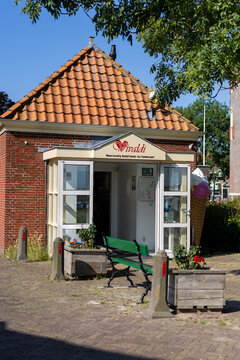 Enkhuizen, Netherlands - July 13, 2026: Vivaldi ice cream shop in a small brick building with red roof tiles, open doors, a green bench and an ice cream cone sign outside.