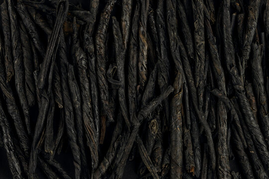 Kuding spear tea displayed on a dark surface, showcasing its twisted texture and rich color