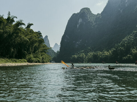 Guilin, China - 10 October 2024: View of a fisherman casting a traditional net on the Li River amidst the iconic karst mountains of Yangshuo County.