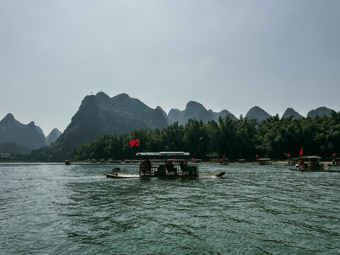 Guilin, China - 10 October 2024: View of bamboo rafts with tourists on the Li River in Yangshuo County surrounded by karst mountains.