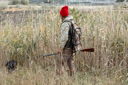A hunter with a gun in camouflage clothing. A gentleman with a gun, medium shot, unrecognizable.