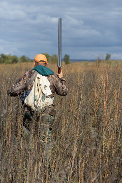 A hunter with a gun in camouflage clothing. A gentleman with a gun, medium shot, unrecognizable.