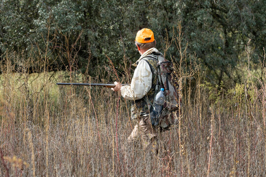 A hunter with a gun in camouflage clothing. A gentleman with a gun, medium shot, unrecognizable.