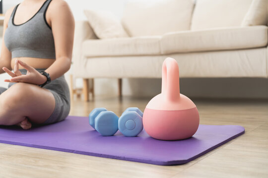 Woman practicing meditation with yoga accessories on purple mat in living room for wellness and mindfulness