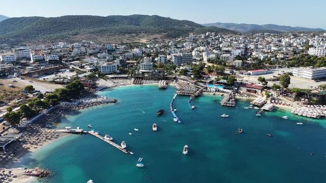 High angle drone shot of Saranda beachfront at dusk, luxury resort town in Albanian Riviera, Ionian sea. Saranda cityscape at night, pedestrian boulevard, public beach and coastal architecture, Albani