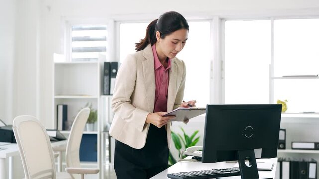 Young businesswoman hand holding pen taking notes , sitting at desk with laptop , analyzing information.