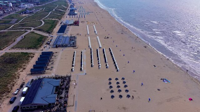 Aerial view video clip of Katwijk aan Zee beach resort, Zee en Zon beach pavilion, beach cabins, windbreaks, coastal dunes, and North Sea horizon in South Holland, Netherlands