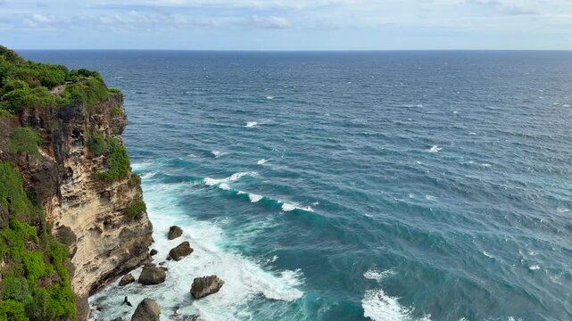 Dramatic coast under Uluwatu Temple. It is a sacred, 10th-century Balinese sea temple perched on a 70-meter-high cliff edge in Pecatu, Bali.