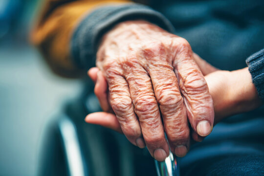 Hands of an elderly man and a young woman caring for him show connection and support. Background is blurred to focus on their hands