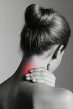 A person is seen from behind, touching their neck while appearing to experience pain. The area shows a red light suggesting discomfort