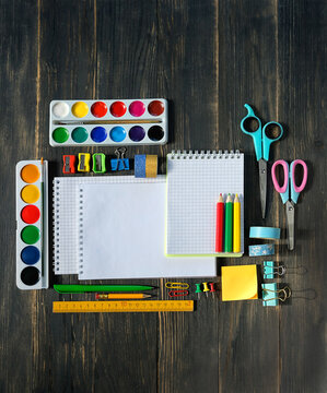 set of accessories, school stationery - pencils, watercolor palette, notebooks on wooden table. Back to school, education, Knowledge Day, 1 september, creativity, artistic art concept. top view