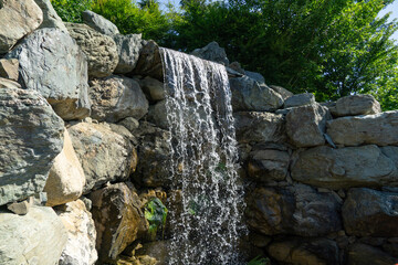 Otaki, a big waterfall cascades over gray rocks, surrounded by greenery. in Japanese garden. Public landscape park of Krasnodar or Galitsky park © MarinoDenisenko