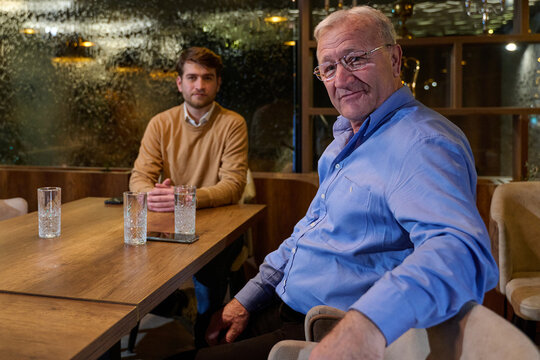Older Man and Younger Colleague Having a Casual Business Meeting in a Cozy Restaurant