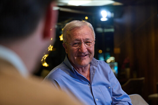 Smiling Senior Man Conversing in a Cozy Restaurant During an Evening Out With a Friend