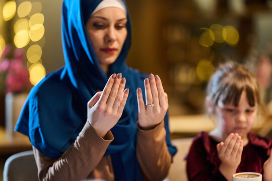 Muslim Mother And Daughter Praying Together At Home Before A Meal