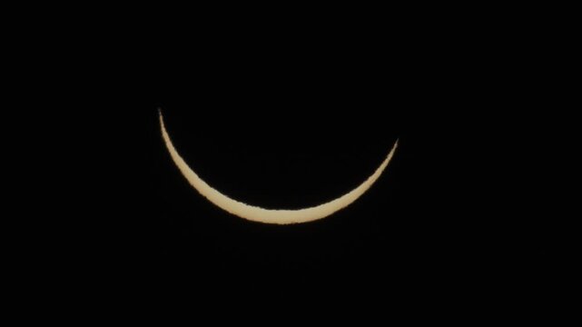 Telephoto footage of partial solar eclipse on August 12, 2026 in Portugal. Thin sun crescent movement in the dark sky, captured with solar filter.