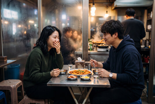 Smiling couple sharing a casual meal at a small urban table in a cozy rainy night eatery for lifestyle background and banner design
