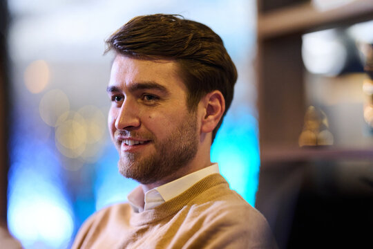 Smiling Young Man In Casual Sweater Portrait With Warm Indoor Bokeh Lighting And Relaxed Expression