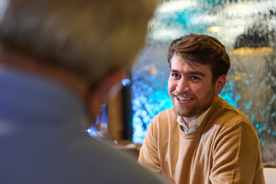 Friendly Business Conversation Between Young Man And Colleague During Casual Meeting At Office Cafe