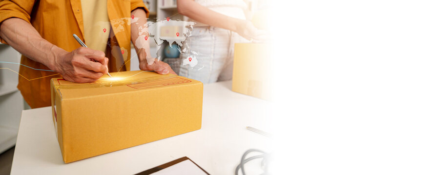 Cropped view of worker writing address on parcel box with global logistics overlay