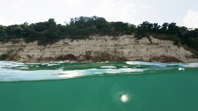 Slow Motion Split View Rocky Sea Coast and Emerald Water