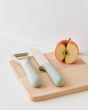 Wide grip kitchen knife and peeler on a pale wooden board