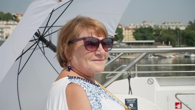 Senior woman uses an umbrella and SPF sunscreen protection on a boat cruise. Smart multi layer UV defense keeps mature skin safe from sunlight. Confident skincare routine prevents photoaging.