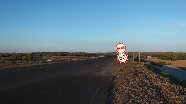 Fresh Asphalt Highway with Speed Limit Sign Across Arid Steppe Landscape
