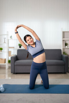 Young woman workout stretching arms overhead  at home in  living room.