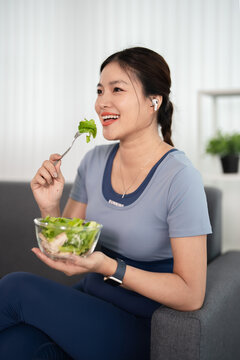 Healthy young woman having salad after work out at home, sport and healthy food lifestyle concept.